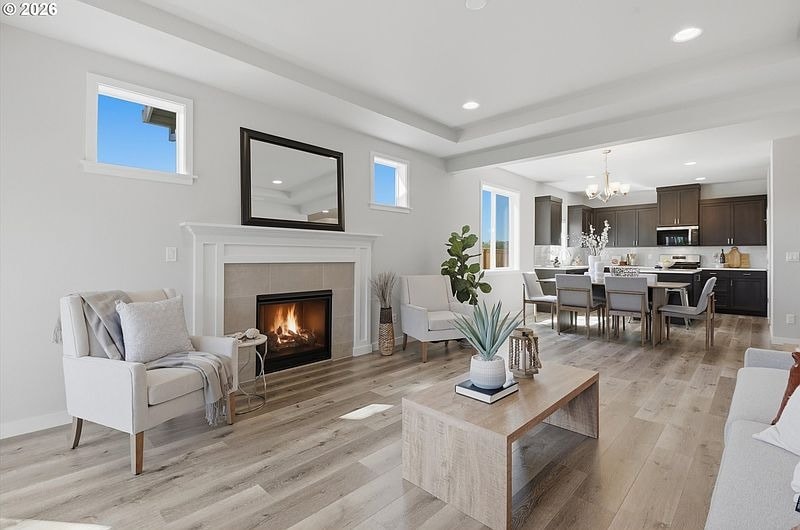 A staged living room with a fireplace reading nook opening into the dining and kitchen