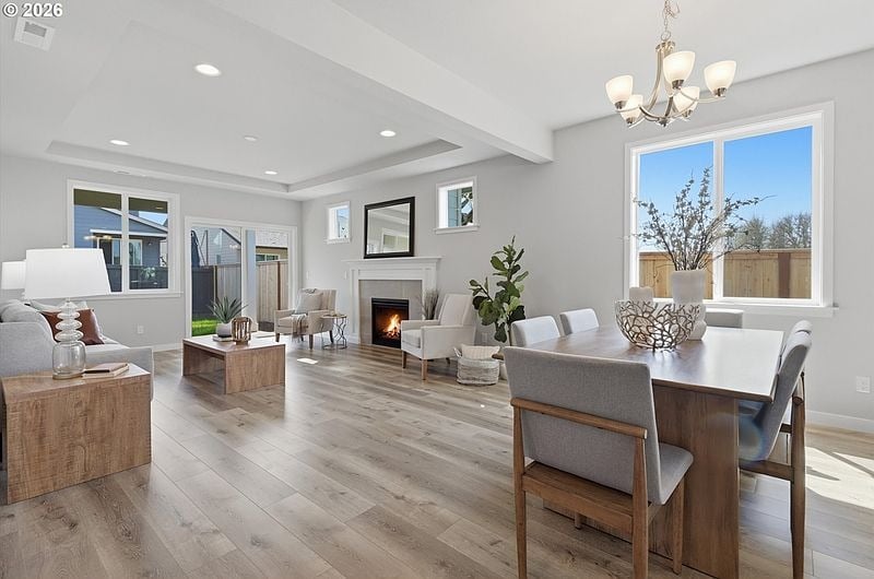 A staged open-concept living and dining room with a fireplace and large windows
