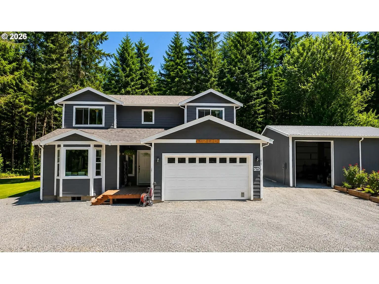 A two-story home with a covered entry next to a large detached shop with an open garage door
